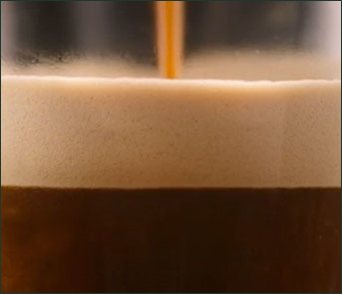 Close-up of rich, foamy espresso being poured into a glass